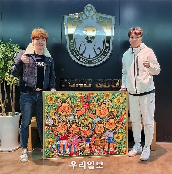 한상윤 작가(왼쪽)과 이동국 선수(오른쪽)가 ‘행복한패밀리’ 작품을 전달 받고 있다. 